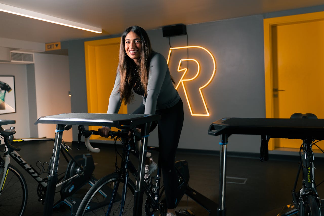 Smiling young woman enjoying a workout on a stationary bike in a Bahrain gym.